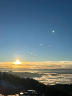 a car parked on a hill with the sun rising above the clouds at Ramondia, Kopaonik in Kopaonik