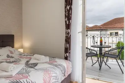 a bedroom with a bed and a balcony with a table at Lucky Lux 1 i 2 Vrnjačka Banja in Vrnjačka Banja