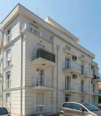 a white building with cars parked in front of it at Lucky Lux 1 i 2 Vrnjačka Banja in Vrnjačka Banja