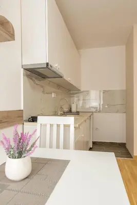 a kitchen with white cabinets and a vase with purple flowers at Lucky Lux 1 i 2 Vrnjačka Banja in Vrnjačka Banja