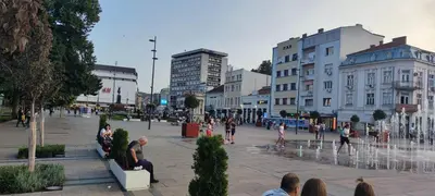 a group of people sitting around a fountain in a city at Топ соба 12 in Niš