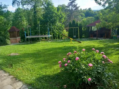 a yard with a park with a playground and pink flowers at Vila Verica in Vrnjačka Banja