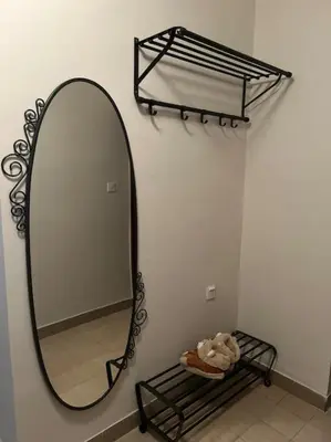 a mirror on a wall with a shelf and a basket at Jordan Apartman in Niška Banja