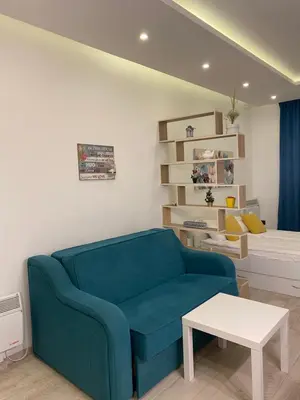 a living room with a blue couch and a bed at Snežna pahuljica P19 in Kopaonik
