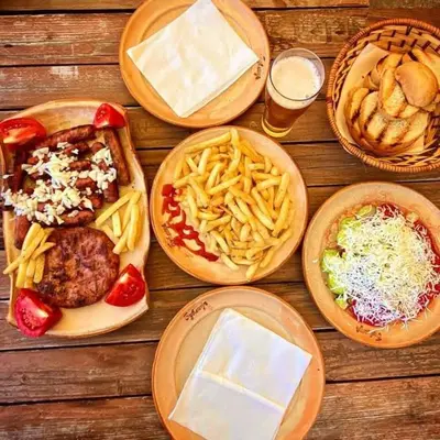 a wooden table topped with plates of food and fries at Krčma u Planini in Bojnik