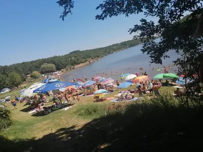 a crowd of people on a beach with umbrellas at Krčma u Planini in Bojnik