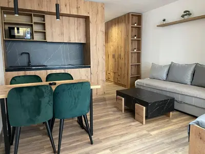 a living room with a couch and a table and chairs at Grand Apartman Kopaonik in Kopaonik