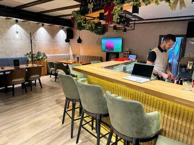 a man standing at a bar with a laptop at Grand Apartman Kopaonik in Kopaonik