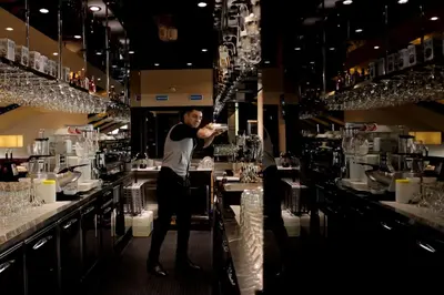a man standing behind the bar of a restaurant at Orbis Design Hotel & Spa in Paraćin