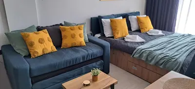 a living room with a blue couch with yellow pillows at TopView Milmari N87 in Kopaonik