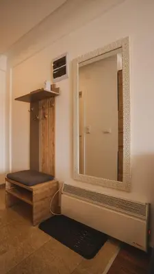 a mirror on the wall of a bathroom with a bench at Milmari Apartman Lucky L03 in Kopaonik