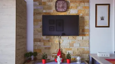 a living room with a tv on a brick wall at Milmari Apartman Lucky L03 in Kopaonik