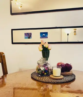 a table with a vase of flowers and a candle at Jolly Kop PetkoSKI Apartman in Kopaonik