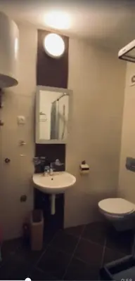 a bathroom with a white sink and a toilet at Jolly Kop PetkoSKI Apartman in Kopaonik