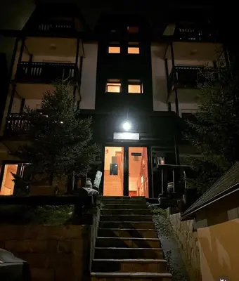 a building with a staircase leading to a door at night at Jolly Kop PetkoSKI Apartman in Kopaonik