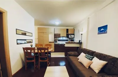 a living room with a couch and a table and a kitchen at Jolly Kop PetkoSKI Apartman in Kopaonik
