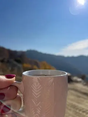 a person holding a cup of coffee on a table at Kopaonik apartment A05 in Kopaonik