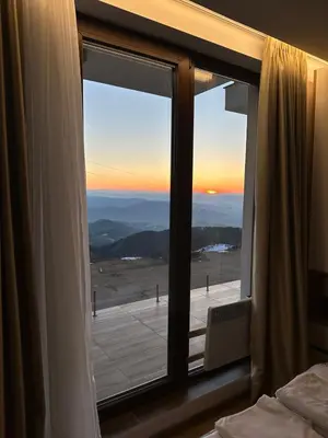 a bedroom window with a view of the sunset at Kopaonik apartment A05 in Kopaonik