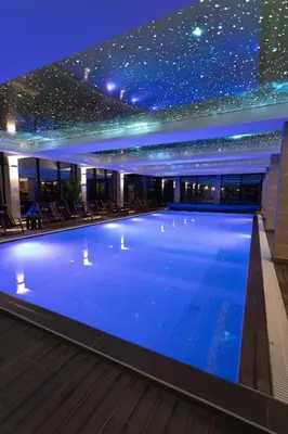 a large swimming pool in a building at night at Ibis Lux Milmari Apartman N51 Kopaonik Panorama Spa in Kopaonik