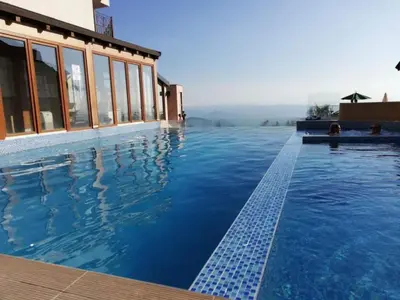 a swimming pool with blue water in front of a building at Ibis Lux Milmari Apartman N51 Kopaonik Panorama Spa in Kopaonik