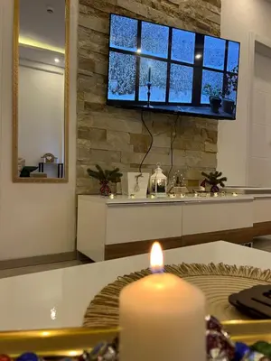 a candle on a table with a television on a wall at Milmari N lux Sena in Kopaonik