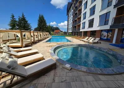 a swimming pool with lounge chairs and a building at Harmony, Residence Hill A85 in Kopaonik