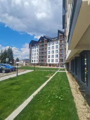 a building with a green lawn next to a building at Kopaonik-Residence Hill Repnica A71 in Cajetina