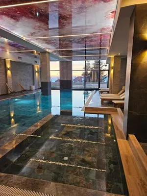 a swimming pool in a building with a large window at Kopaonik-Residence Hill Repnica A71 in Cajetina