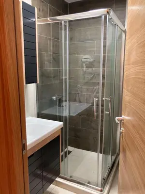 a shower with a glass door next to a sink at Pogled Apartman Kopaonik in Kopaonik