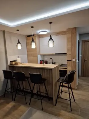 a kitchen with a bar with four chairs in it at Apartman 318 - Sunčana Planina in Kopaonik