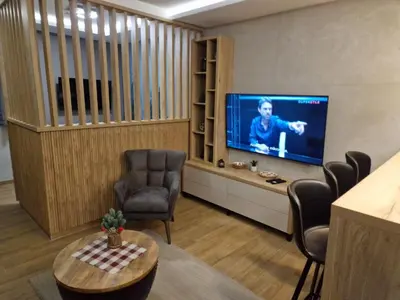 a living room with a flat screen tv and chairs at Apartman 318 - Sunčana Planina in Kopaonik