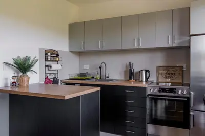 a kitchen with black cabinets and a sink and a stove at Apartman Rustic 85m2 in Kopaonik