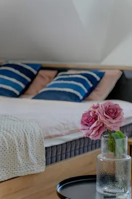 a vase with flowers on a table in front of a bed at Apartman Rustic 85m2 in Kopaonik