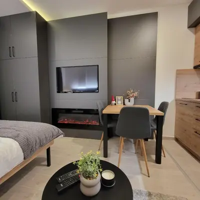 a bedroom with a bed and a table and a television at PIK Apartmani - Milmari in Kopaonik