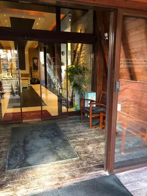 an open glass door of a building with a bench at Kop apartman I01 in Kopaonik