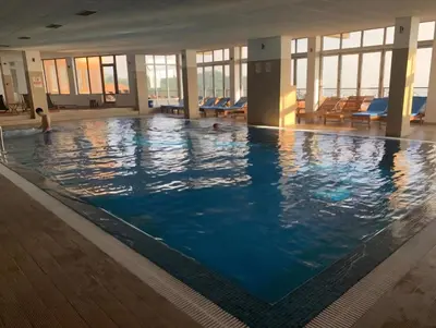 a large swimming pool in a building with windows at Apartman Adut Kop. in Kopaonik