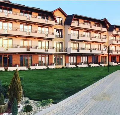 a large apartment building with a lawn in front of it at Apartman Adut Kop. in Kopaonik