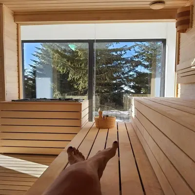 a person laying on a bench in a room with a window at Sunčani breg resort & spa in Kopaonik