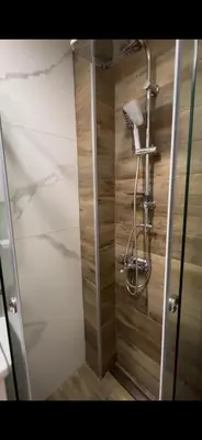 a shower in a bathroom with a wooden wall at Studio M in Kopaonik