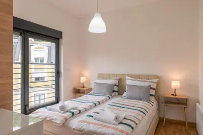 two beds in a room with a large window at Apartmani Central 11 & Free parking in Vrnjačka Banja