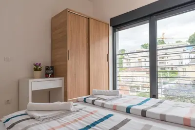 two beds in a room with a large window at Apartmani Central 11 & Free parking in Vrnjačka Banja