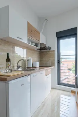 a kitchen with white cabinets and a window at Apartmani Central 11 & Free parking in Vrnjačka Banja