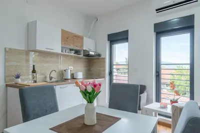 a kitchen with a table with flowers in a vase at Apartmani Central 11 & Free parking in Vrnjačka Banja
