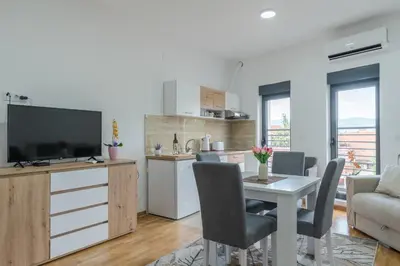 a kitchen and living room with a table and a television at Apartmani Central 11 & Free parking in Vrnjačka Banja