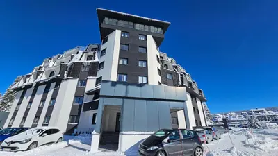 a tall building with cars parked in front of it at Silver Pine Kopaonik in Kopaonik