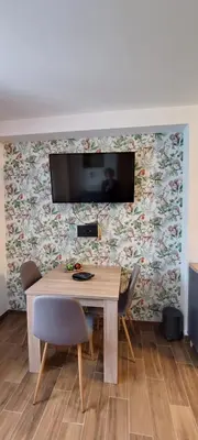 a dining room table with chairs and a tv on a wall at Apartman Jovanovic,Kopaonik in Kopaonik