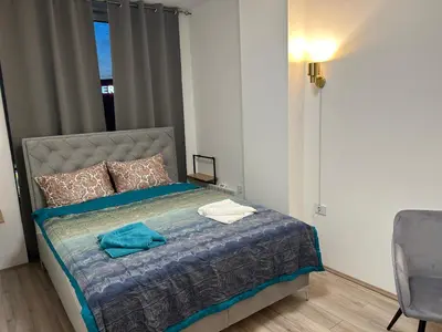 a bedroom with a bed and a chair and a window at De Lux Nedeljkovic President in Jagodina