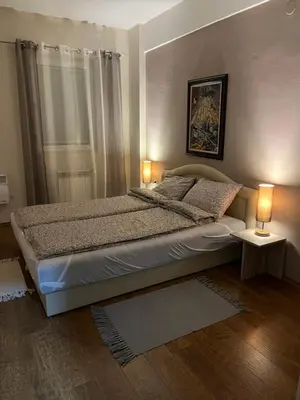 a bedroom with a bed with two lamps on it at Central Apartments in Zaječar