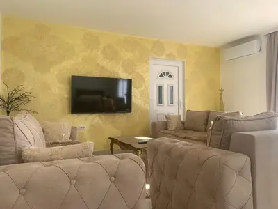 a living room with couches and a television on a wall at DINA LUX Apartman in Jagodina