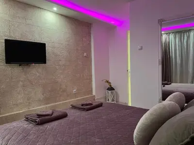 a bedroom with two beds with purple lights on the wall at Apartman Rose in Kruševac